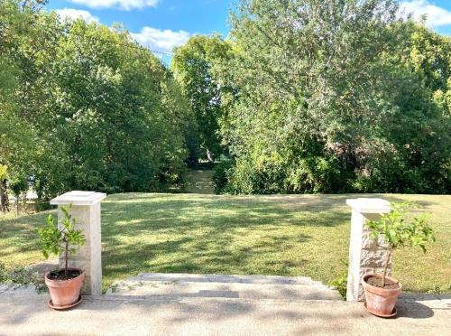 Stunning bedroom overlooking the Charente في Bourg-Charente: اثنين من النباتات الفخارية موجودة على عامدين في حديقة