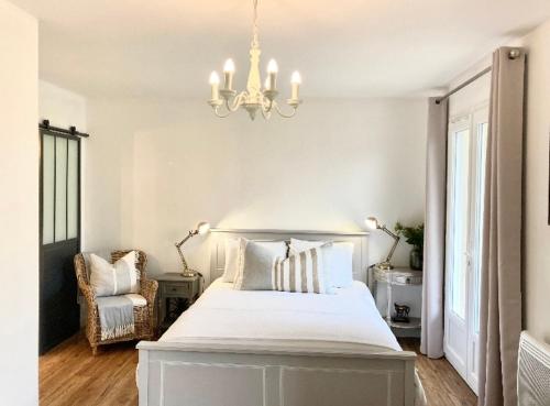 a bedroom with a large white bed and a chandelier at Stunning bedroom overlooking the Charente in Bourg-Charente