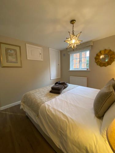 um quarto com uma grande cama branca e um lustre em Charming 1 Bedroom Cottage Style Maisonette by HP Accommodation em Milton Keynes