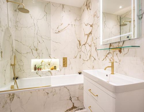 a white bathroom with a sink and a tub at Be London - The De Beauvoir Residences in London