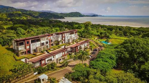 an aerial view of a building on a hill next to the ocean at Vista Lapas Nativa Resort in Jacó