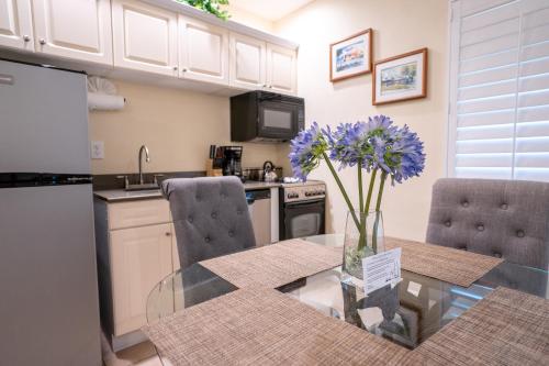 a kitchen with a glass table with purple flowers in a vase at The Capri at Siesta in Siesta Key