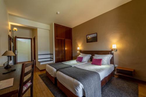 a bedroom with a large bed with two pink pillows at Hotel Vista Bela do Gerês in Outeiro