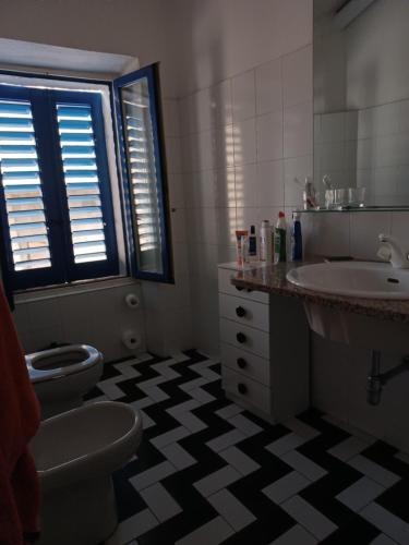 een badkamer met een wastafel, een toilet en een wastafel bij Villa TERRA in Oliena