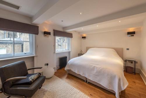 a bedroom with a bed and a chair and windows at Stunning 3 Bed Townhouse in the heart of Mayfair in London