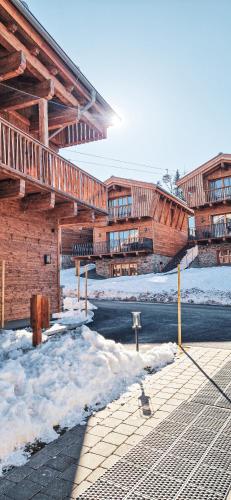 a wooden building with snow on the ground at ZAGLGUT HOTEL-CHALETS Wellness & Views with Summer Card Included in Kaprun