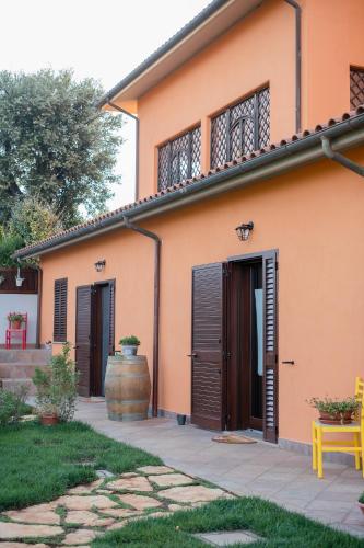 an orange house with brown doors and a yellow bench at Agriturismo I Grappoli in Alberese