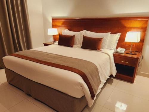 Una cama grande en una habitación de hotel con dos lámparas. en Imperial Hotel Apartments, en Riad