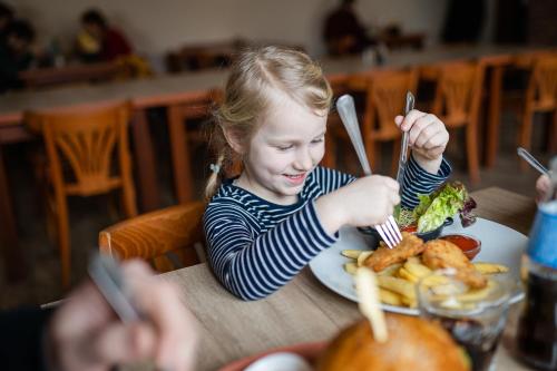 a little girl sitting at a table with a plate of food at Hotel Prácheň in Horažďovice