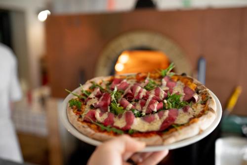 a person holding a pizza on a plate at Hotel Prácheň in Horažďovice