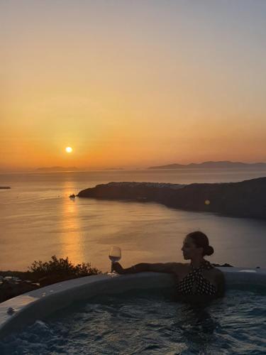 a woman sitting in a bath tub with a glass of wine at White Pearl Cavalieri in Imerovigli