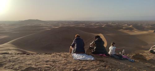a group of people sitting on top of a desert at Erg Chigaga Regency Camp in El Gouera