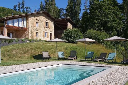 a swimming pool in front of a house with chairs and umbrellas at Gîte de luxe 4 étoiles in Saint-Antoine