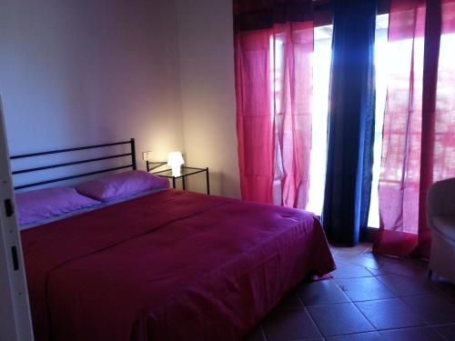 a bedroom with a bed with purple sheets and windows at Villa Serena B in Stintino
