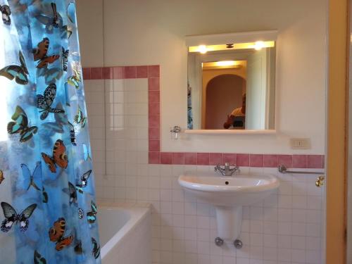 a bathroom with a sink and a shower curtain with butterflies at Villa Serena B in Stintino