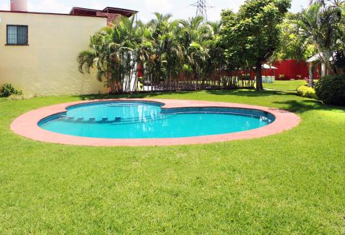 a small swimming pool in the grass in a yard at Casa Palmera con Aire acondicionado Alberca Wifi cocina y TV in Emiliano Zapata