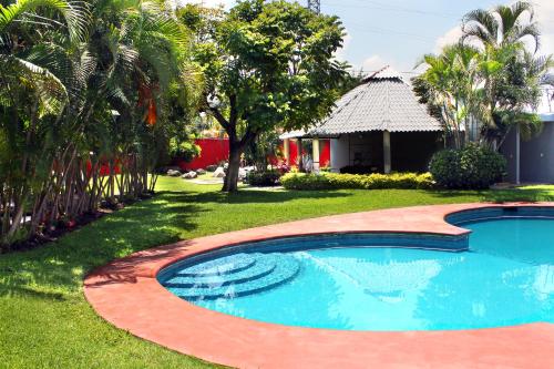 a swimming pool in a yard next to a house at Casa Palmera con Aire acondicionado Alberca Wifi cocina y TV in Emiliano Zapata