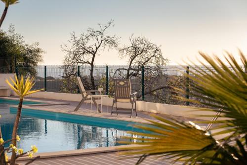 two chairs and a table next to a swimming pool at Apartamento Sunset on the Sea in Albufeira