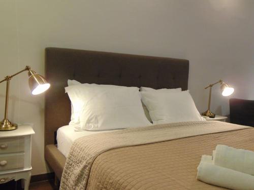 1 dormitorio con 1 cama con almohadas blancas y 2 lámparas en Metropolis A1-Γοητευτική Σουίτα, en Atenas