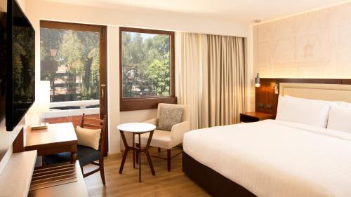 a hotel room with a bed and a desk and a window at Marriott Puebla Hotel Meson del Angel in Puebla