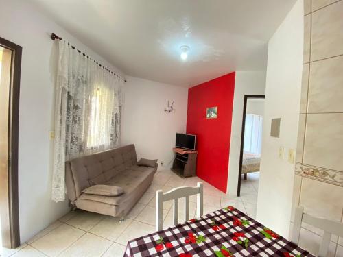 uma sala de estar com um sofá e uma parede vermelha em Residencial Marítimos em Torres