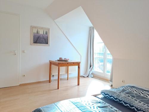 um quarto com uma cama, uma mesa e uma janela em Ruhepol am Meer - Apartment mit Balkon em Bastorf