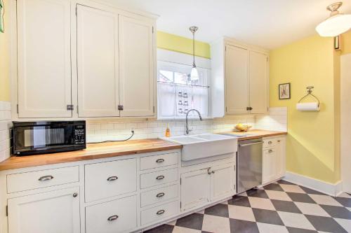 a kitchen with white cabinets and a sink and a microwave at Charming Eugene Vacation Home 1 Mi to Dtwn! in Eugene