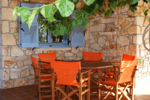 a wooden table and chairs in front of a stone wall at Lithos stone house (Ionio holidays) in Vasilikos