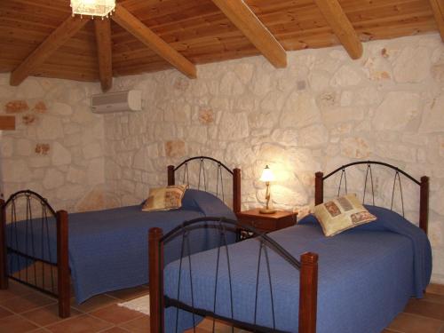 2 camas en una habitación con una pared de piedra en Lithos stone house (Ionio holidays), en Vasilikos