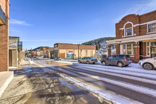 a snowy street in a small town with cars parked at Convenient Lead Vacation Rental! in Lead