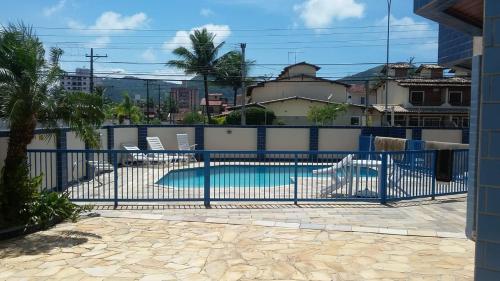 ein blauer Zaun um einen Pool mit Stühlen in der Unterkunft Lindo Apto Praia Martin de Sá em Condomínio com Piscina, Estacionamento, WI-FI 150mbps,PERTO DO MAR!!! in Caraguatatuba