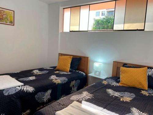 1 dormitorio con 2 camas y ventana en Lindo dpto con vista al jardin, internet y cable, en Lima