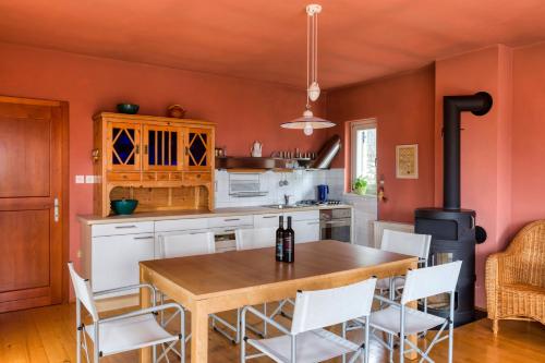 eine Küche mit orangefarbenen Wänden sowie einem Holztisch und Stühlen in der Unterkunft Vila Nadrožica 