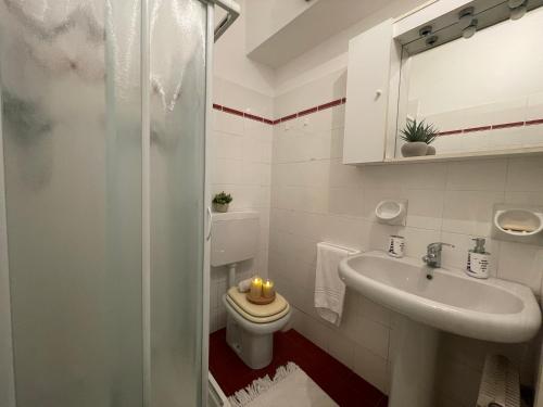 a bathroom with a toilet and a sink with candles at Relax in Piscina - Free Parking e ampio Giardino in Loano