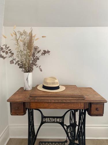 a hat on a wooden table with a vase of flowers at les chambres de pauline appartements in Albertville
