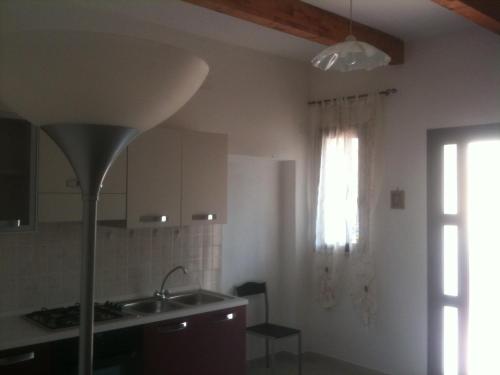 cocina con fregadero, ventana y lámpara en Casa Olbia, en Olbia