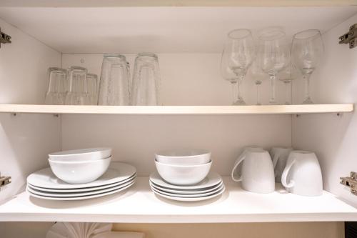 a white shelf with dishes and glasses on it at The Capri at Siesta in Siesta Key