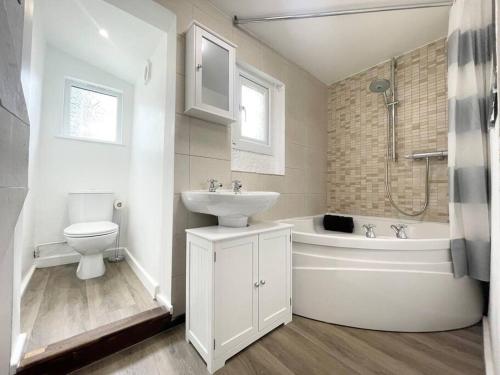 a bathroom with a sink and a tub and a toilet at Cheerful Home Short Drive to Beautiful Beach in Redruth