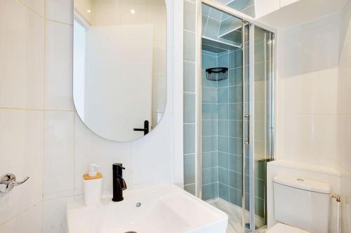 une salle de bain blanche avec un lavabo et une douche dans l'établissement Magnifique 3 pièces Paris 18ème, à Paris