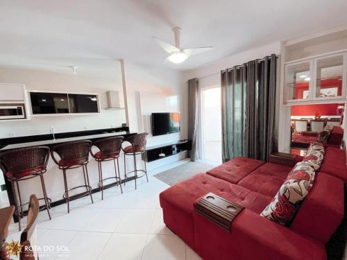 ein Wohnzimmer mit einem roten Sofa und einer Küche in der Unterkunft Res. Nona Martha in Bombinhas