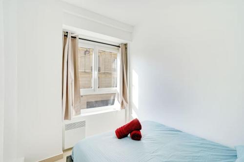 un osito de peluche rojo sentado en una cama en un dormitorio en Magnifique 3 pièces Paris 18ème, en París