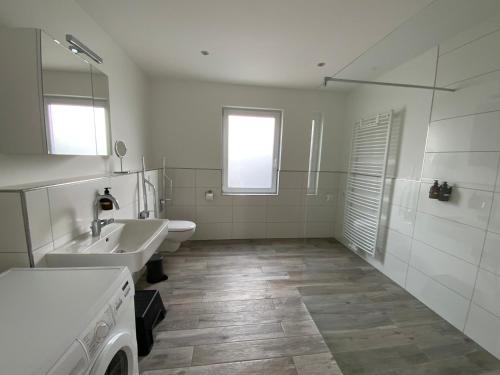 ヴンストルフにあるFliegender Holländerの洗面台2つとシャワー付きの白いバスルーム