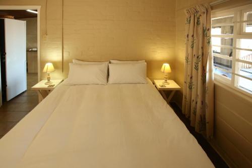 a large white bed in a room with two lamps at Oppi Stuppi Langebaan in Langebaan