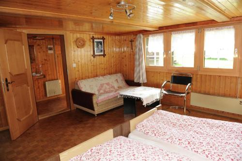 een kamer met 2 bedden en een tafel en een bank bij Chalet Talblick in Saas-Grund