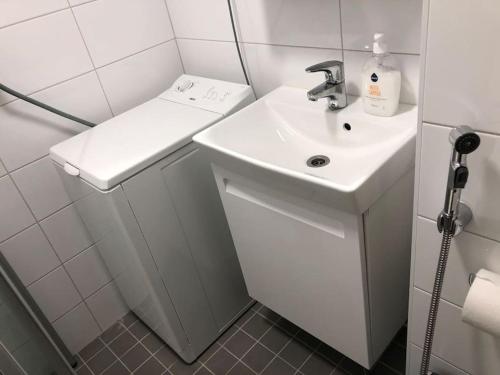 a white bathroom with a sink and a shower at Stylish spacious studio near centre by the sea in Helsinki
