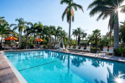 a swimming pool with palm trees and chairs at The Capri at Siesta in Siesta Key