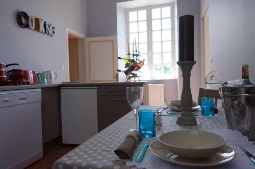 a kitchen with a table with plates and a wine glass at Gîtes du château de la Motte in Joué-du-Plain