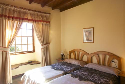 1 dormitorio con 2 camas y ventana en Casa Rural Olga en El Paso