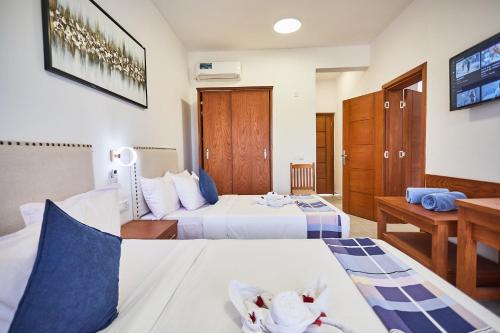 a hotel room with two beds and a desk at Malika Nungwi Hotel in Nungwi