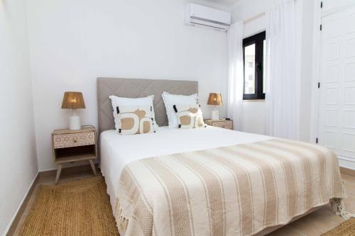 a white bedroom with a large white bed with pillows at Oura 7 in Albufeira